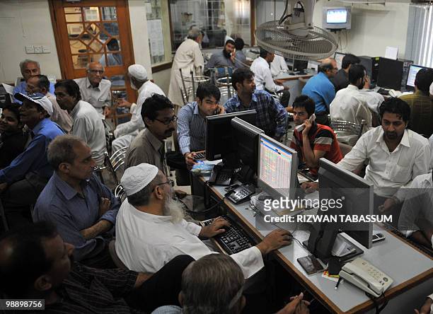 Pakistani stock dealers work at a brokerage house during a trading session in Karachi on May 7, 2010. The benchmark Karachi Stock Exchange 100 index...