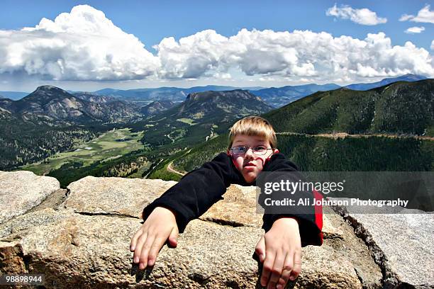 boy hang on a rocky mountain - ali stone stock pictures, royalty-free photos & images