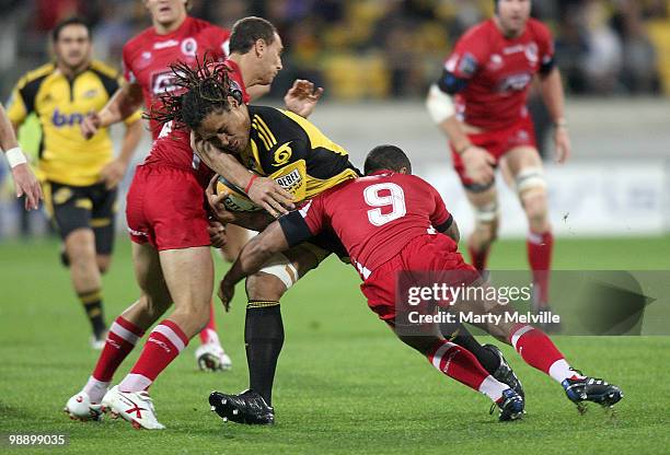 Rodney So'oialo of the Hurricanes is tackled by Will Gena and Quade Cooper of the Reds during the round 13 Super 14 match between the Hurricanes and...