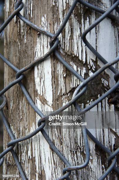 chainlink wire fencing on a wooden post with peeling paint - bowral new south wales stock pictures, royalty-free photos & images