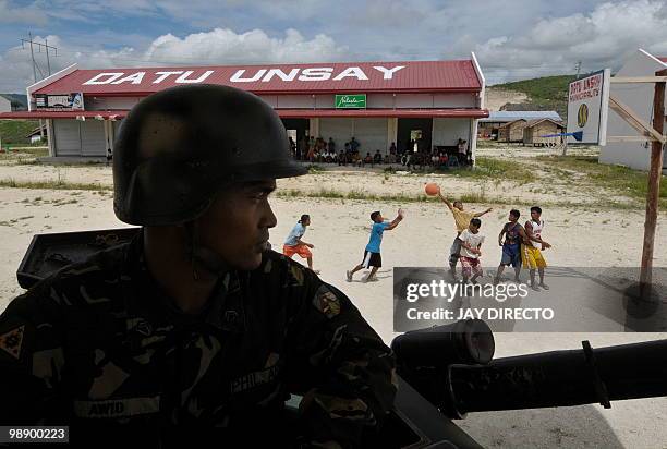 Soldier aboard an armoured personnel carrier guards a bus terminal in southern Maguindanao province in the Philippines as men play basketball on a...