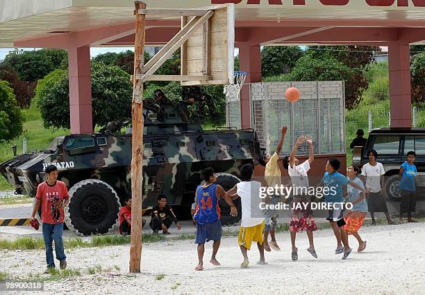 Soldiers aboard an armoured personnel carrier guard a bus terminal in southern Maguindanao province in the Philippines as people play basketball on a...