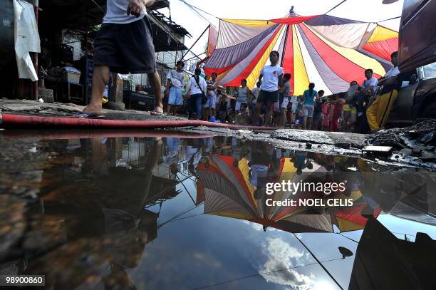 Residents stay on a tent after a fire raced through a squatter area in Malabon, north of Manila on May 7, 2010. Around 100 houses were burned to the...