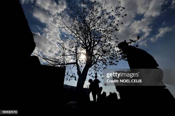 Resident are silhoetted as they salvage their belongings in the debris after a fire gutted a slum area in Malabon, north of Manila on May 7, 2010....