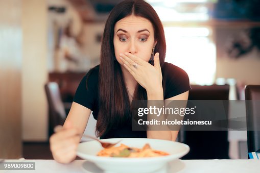 Woman Feeling Sick While Eating Bad Food in a Restaurant Woman Feeling Sick While Eating Bad Food in a Restaurant