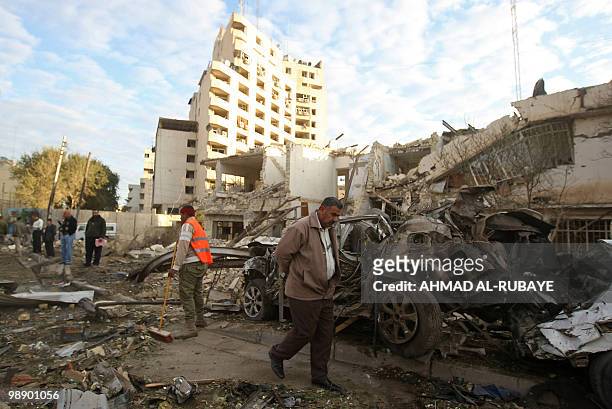 An Iraqi man walks past a municipal worker clearing debris a day after a bomb blast near the Hamra Hotel in Jadriyah, south of Baghdad, on January...