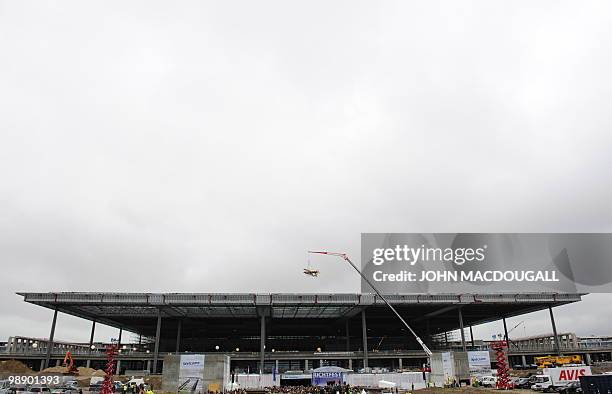 An airplane shaped crown is lifted by a crane over the main terminal of the Berlin-Brandenburg International airport during a traditional "topping...