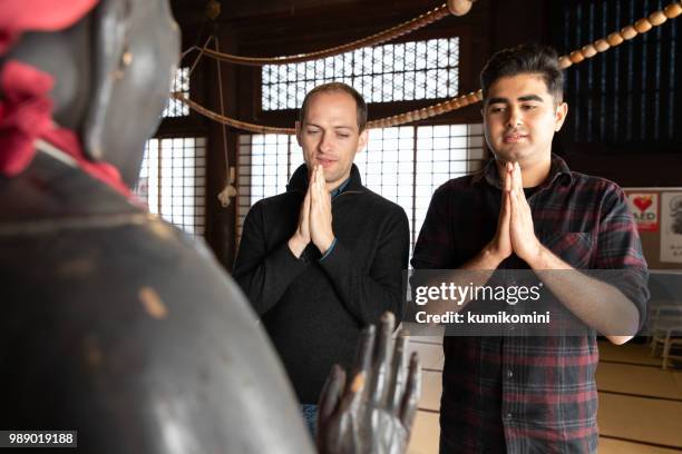 two men praying at temple - kumikomini stock pictures, royalty-free photos & images