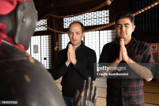 two men praying at temple - kumikomini stock pictures, royalty-free photos & images