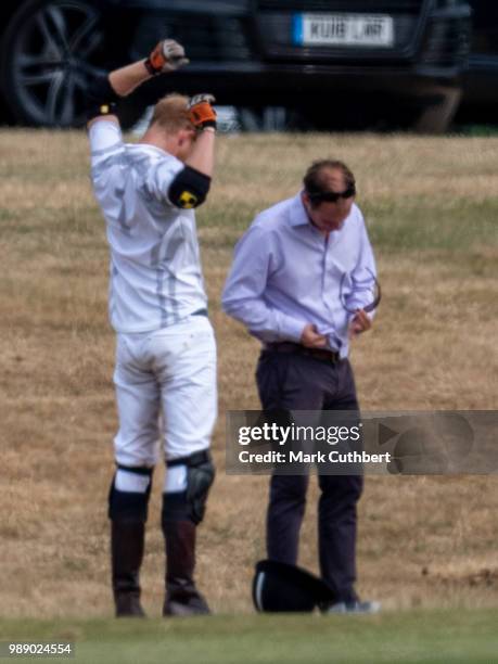 Prince Harry, Duke of Sussex waits for his sunglasses to be cleaned during the Audi Polo Challenge Day 2 at Coworth Park Polo Club on July 01, 2018...