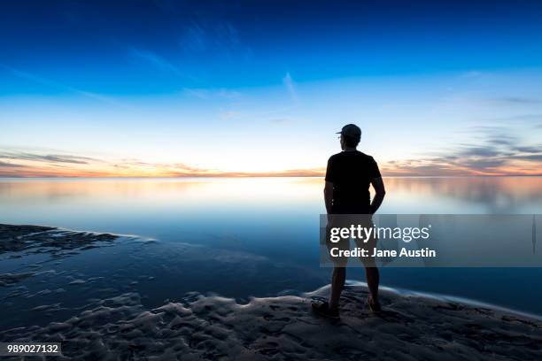man contemplates the sunset at coral bay, western australia. - coral bay australie occidentale photos et images de collection