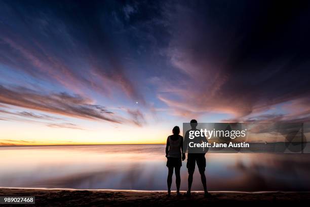 a couple watch the sunset at coral bay on the western australian coast - coral bay australie occidentale photos et images de collection