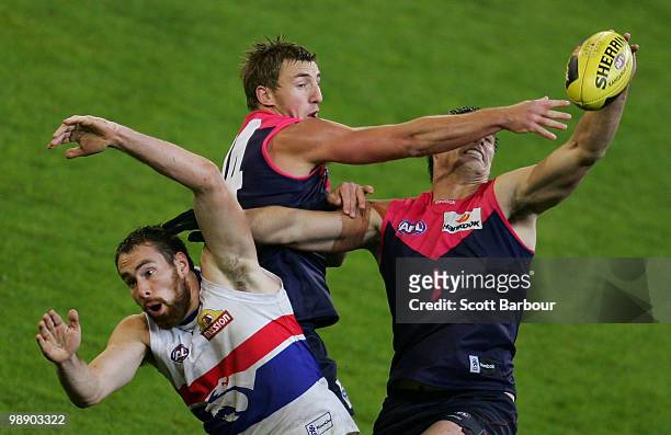 Ben Hudson of the Bulldogs, Lynden Dunn and Paul Johnson of the Demons compete for the ball during the round seven AFL match between the Melbourne...