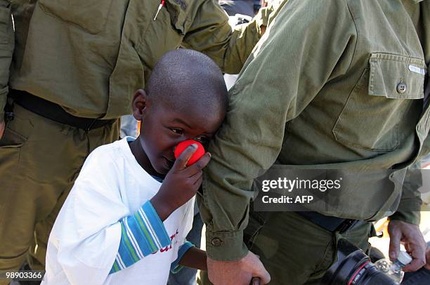 Nine-year-old Haitian child holds the hand of a member of the Israeli rescue team sent to Haiti upon arrival at Ben Gurion airport near Tel Aviv on...