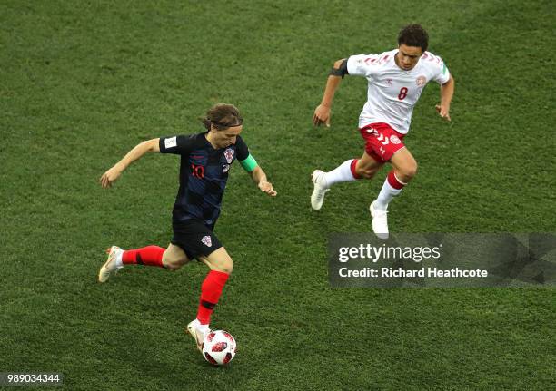Luka Modric of Croatia runs with the ball under pressure from Thomas Delaney of Denmark during the 2018 FIFA World Cup Russia Round of 16 match...