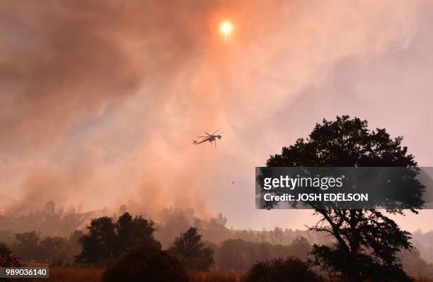 Water dropping helicopter works the scene as the Pawnee fire jumps across highway 20 near Clearlake Oaks, California on July 1, 2018. - More than...