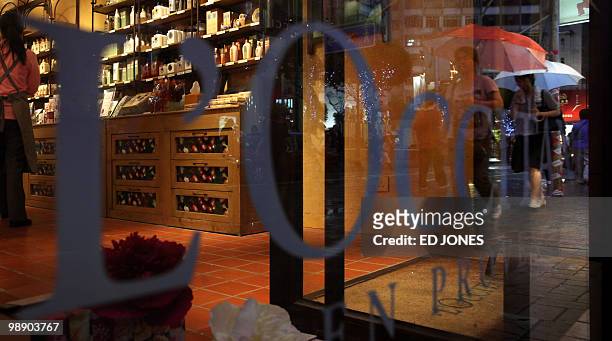 Pedestrians are reflected in the shop window of French cosmetics company L'Occitane, at a branch in the Causeway Bay district of Hong Kong on May 7,...