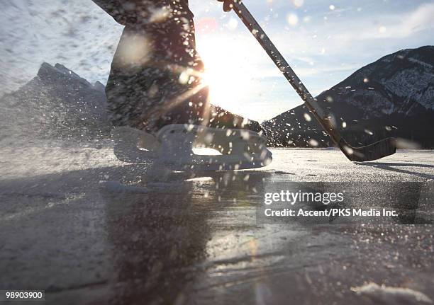 hockey player turns fast on frozen mountain pond - pond hockey stock-fotos und bilder