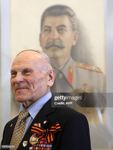 Russian WWII veteran stands near a painting of Soviet dictator Josef Stalin at a museum in Moscow on May 7, 2010. Russian President Dmitry Medvedev...