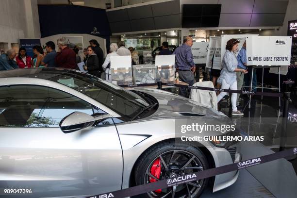 People queue to vote during the presidential election at a polling station on a luxury car dealer in Polanco, Mexico City on July 1, 2018. - Sick of...