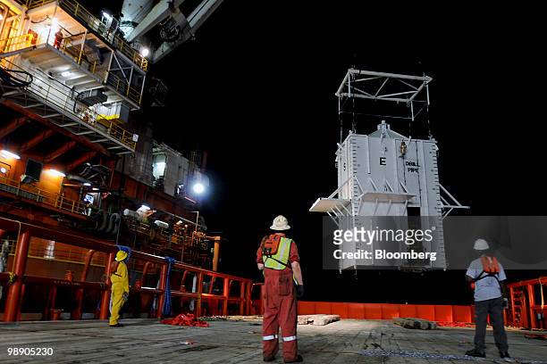 Crewmen aboard the M/V Joe Griffin watch as a cofferdam is hoisted by a crane from the Helix Q4000 mobile offshore drilling unit, left, before being...