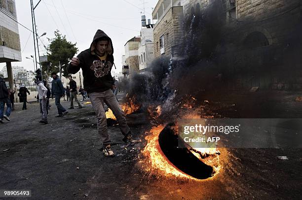 Palestinian demonstrator kicks a burning tyre during clashes with Israeli forces in the West Bank town of Hebron on February 25, 2010. Around 100...