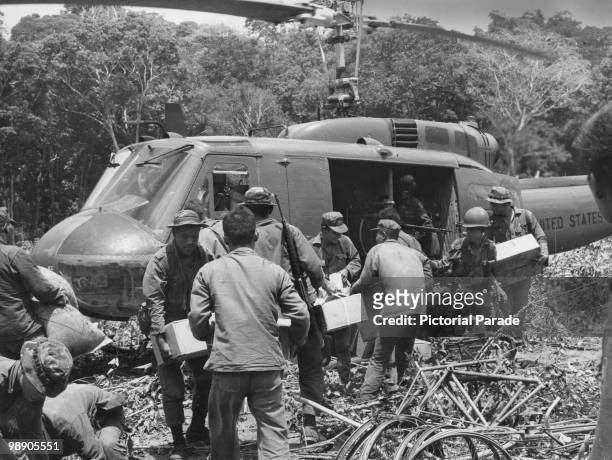 American and South Vietnamese troops loading a helicopter with captured weapons found hidden in the jungle during Operation Binh Tay in Cambodia, 1st...