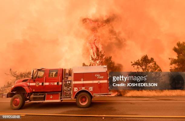 Firefighters scramble to get control as flames from the Pawnee fire jump across highway 20 near Clearlake Oaks, California on July 1, 2018. - More...