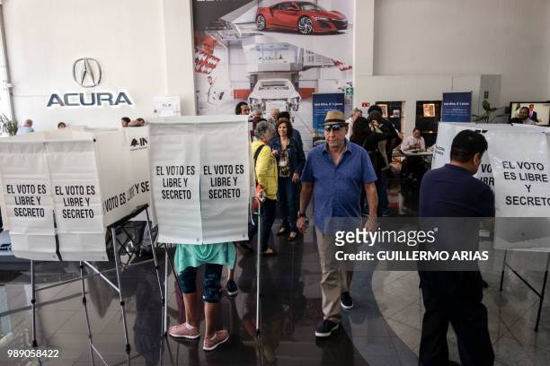People queue to vote during the presidential election at a polling station on a luxury car dealer in Polanco, Mexico City on July 1, 2018. - Sick of...