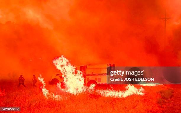 Firefighters scramble to control flames surrounding a fire truck as the Pawnee fire jumps across highway 20 near Clearlake Oaks, California on July...