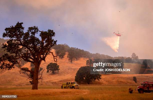 Helicopter drops water on a hillside as firefighters scramble to get control as flames from the Pawnee fire near Clearlake Oaks, California on July...