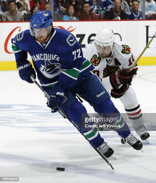 Patrick Sharp of the Chicago Blackhawks skates closely behind as Daniel Sedin of the Vancouver Canucks skates up ice with the puck in Game Three of...