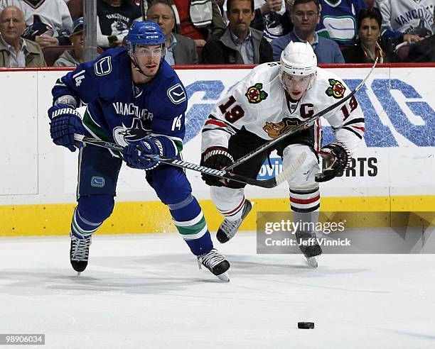 Jonathan Toews of the Chicago Blackhawks and Alex Burrows of the Vancouver Canucks skate after the puck in Game Three of the Western Conference...