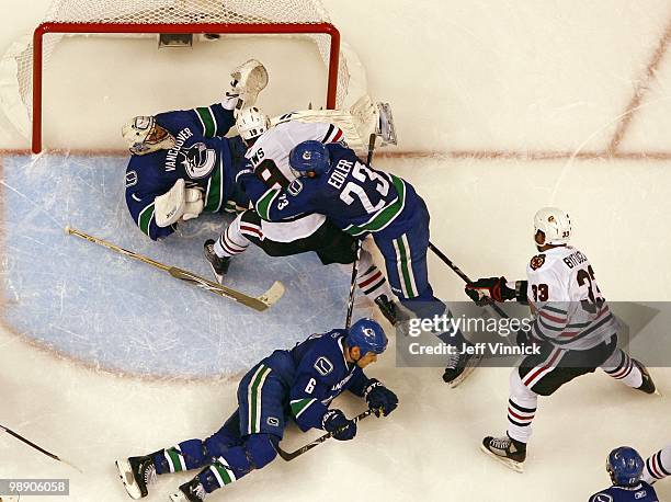 Sami Salo and Alexander Edler of the Vancouver Canucks and Jonathan Toews of the Chicago Blackhawks look on as Dustin Byfuglien of the Chicago...