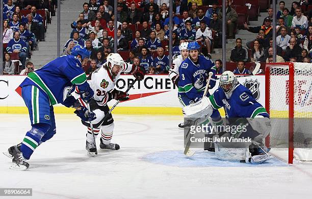 Kevin Bieksa and Andrew Alberts of the Vancouver Canucks and Ben Eager of the Chicago Blackhawks look on as Roberto Luongo of the Vancouver Canucks...