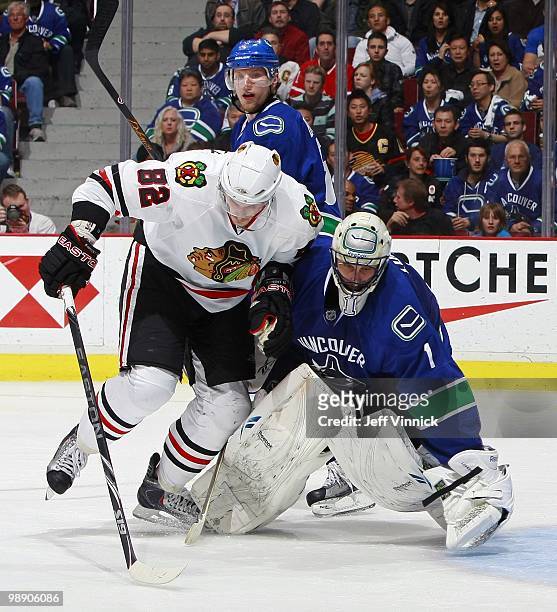 Christian Ehrhoff of the Vancouver Canucks looks on as Tomas Kopecky of the Chicago Blackhawks collides with Roberto Luongo of the Vancouver Canucks...