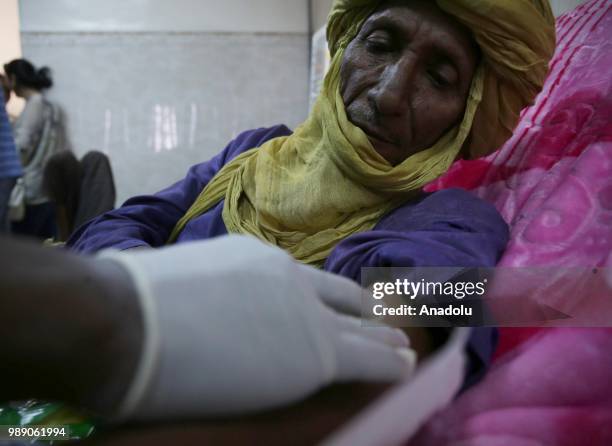 An African migrant patient, who will be repatriated to their countries, receives medical treatment at Tamanrasset Hospital of the refugee camp...