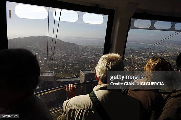 Tourists enjoy the landscape from a cable car on the Table mountain cableway on May 7, 2010 in Cape Town. Table Mountain cableway has been running...