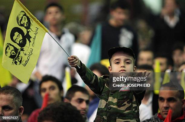 Young Lebanese boy dressed in military fatigue gestures during a ceremony commemorating the second assassination anniversary of Hezbollah commander...