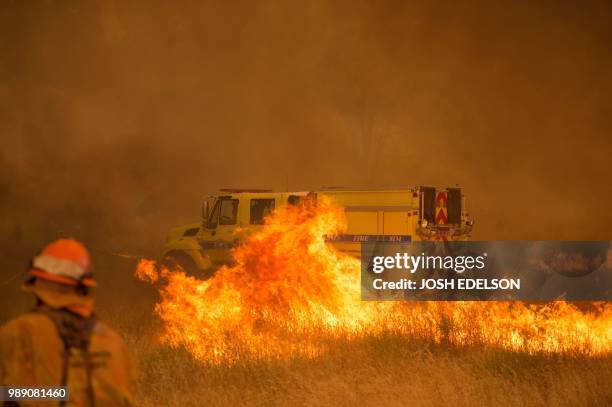 Fire vehicle is surrounded by flames as the Pawnee fire jumps across highway 20 near Clearlake Oaks, California on July 1, 2018. - More than 30,000...