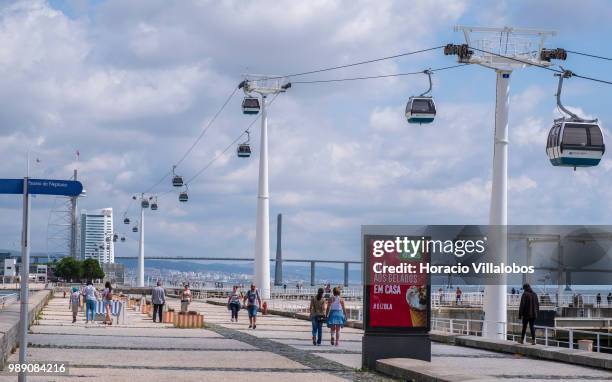 Gondola lifts, a favorite for tourists, and people walking by Parque das Nacoes during a sunny Sunday morning on July 01, 2018 in Lisbon, Portugal....