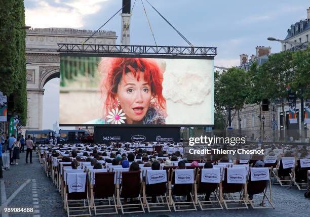 People watch the projection of the movie "Les Visiteurs" during the event "A Sunday at the Cinema" on the Avenue des Champs-Elysees on July 1, 2018...