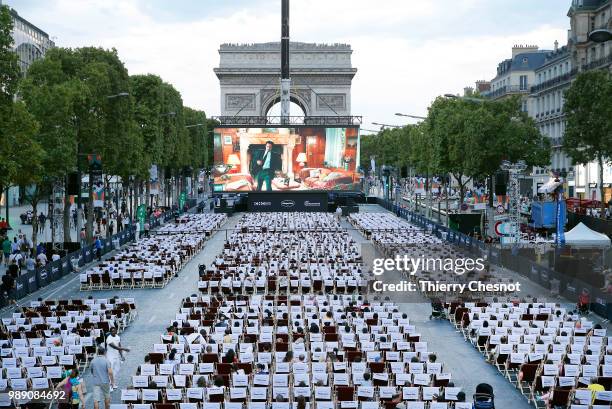 People watch the projection of the movie "Les Visiteurs" during the event "A Sunday at the Cinema" on the Avenue des Champs-Elysees on July 1, 2018...