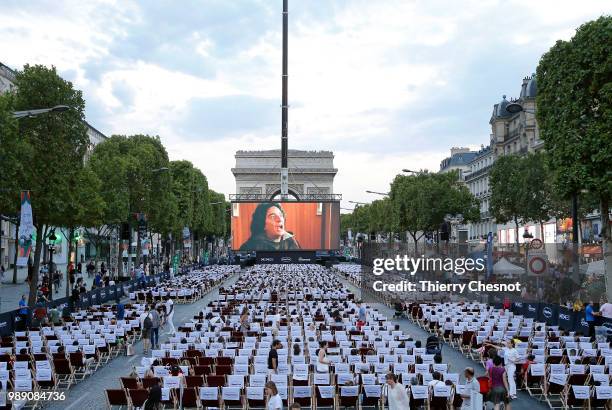 People watch the projection of the movie "Les Visiteurs" during the event "A Sunday at the Cinema" on the Avenue des Champs-Elysees on July 1, 2018...