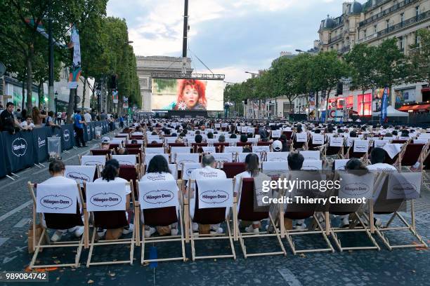 People watch the projection of the movie "Les Visiteurs" during the event "A Sunday at the Cinema" on the Avenue des Champs-Elysees on July 1, 2018...