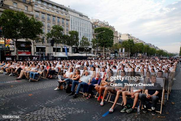 People watch the projection of the movie "Les Visiteurs" during the event "A Sunday at the Cinema" on the Avenue des Champs-Elysees on July 1, 2018...