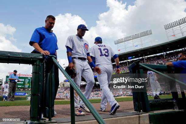 Addison Russell of the Chicago Cubs is escorted off the field by head athletic trainer P.J. Mainville after colliding with Javier Baez , as he made a...