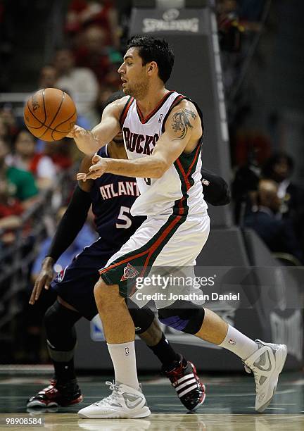 Carlos Delfino of the Milwaukee Bucks passes the ball under pressure from Josh Smith of the Atlanta Hawks in Game Six of the Eastern Conference...