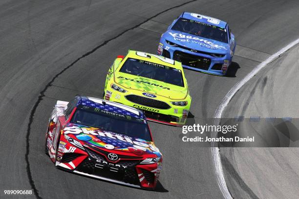 Kyle Busch, driver of the Skittles Red White & Blue Toyota, leads Paul Menard, driver of the Menards/Sylvania Ford, and Chris Buescher, driver of the...