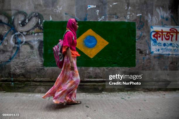 Woman walks near a Brazilian flag in Dhaka, Bangladesh, on July 1, 2018.